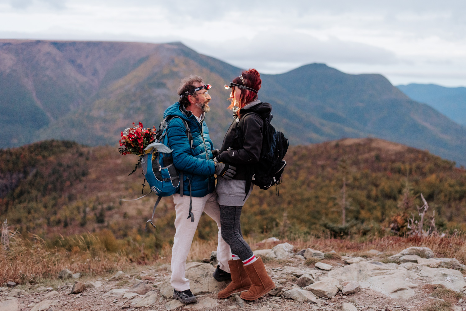 Couple de mariés arrivent au sommet d'une montagne avant le lever du soleil équipé pour leur elopement.