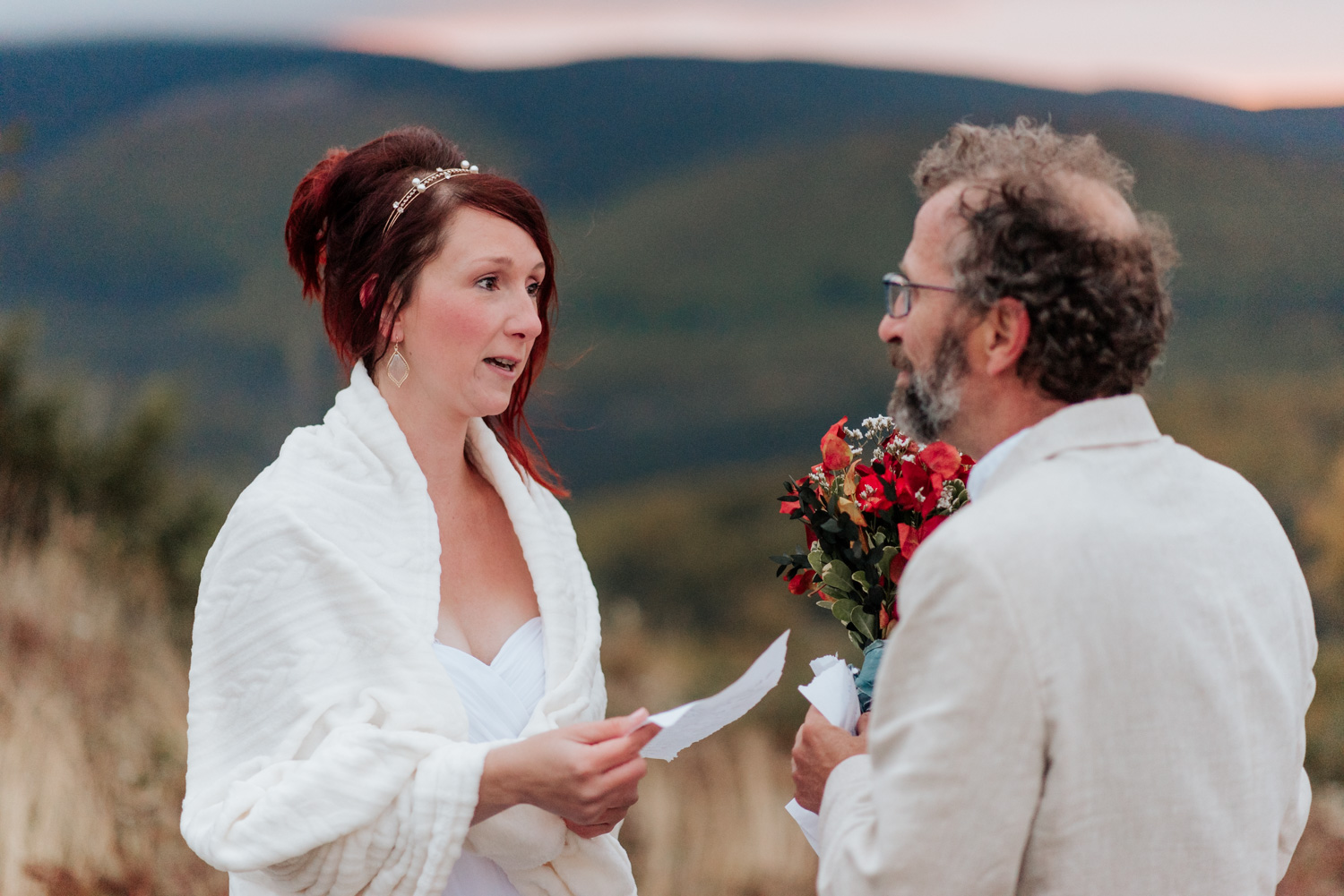 Elopement en Gaspésie au Québec. Les mariés lisent leurs voeux de mariage au sommet des montagnes au lever du soleil.