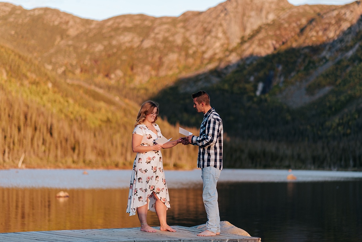 Elopement en Gaspésie alors que les deux mariés lisent leurs voeux de mariage. Les montagnes sont derrière eux.