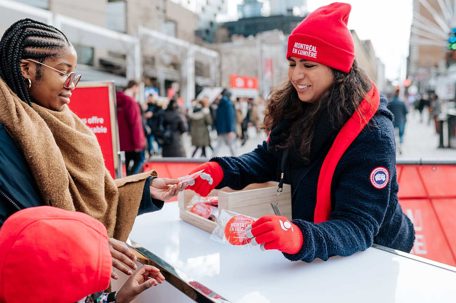 Photographie d'évènement prise lors du Festival Montréal en Lumière à Montréal. On y voit une bénévolé distribuer des items promotionnels.