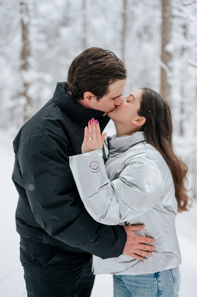 Newly engaged couple kissing in the snow at Lac Spruce in Sutton, Eastern Townships, engagement ring visible on her hand